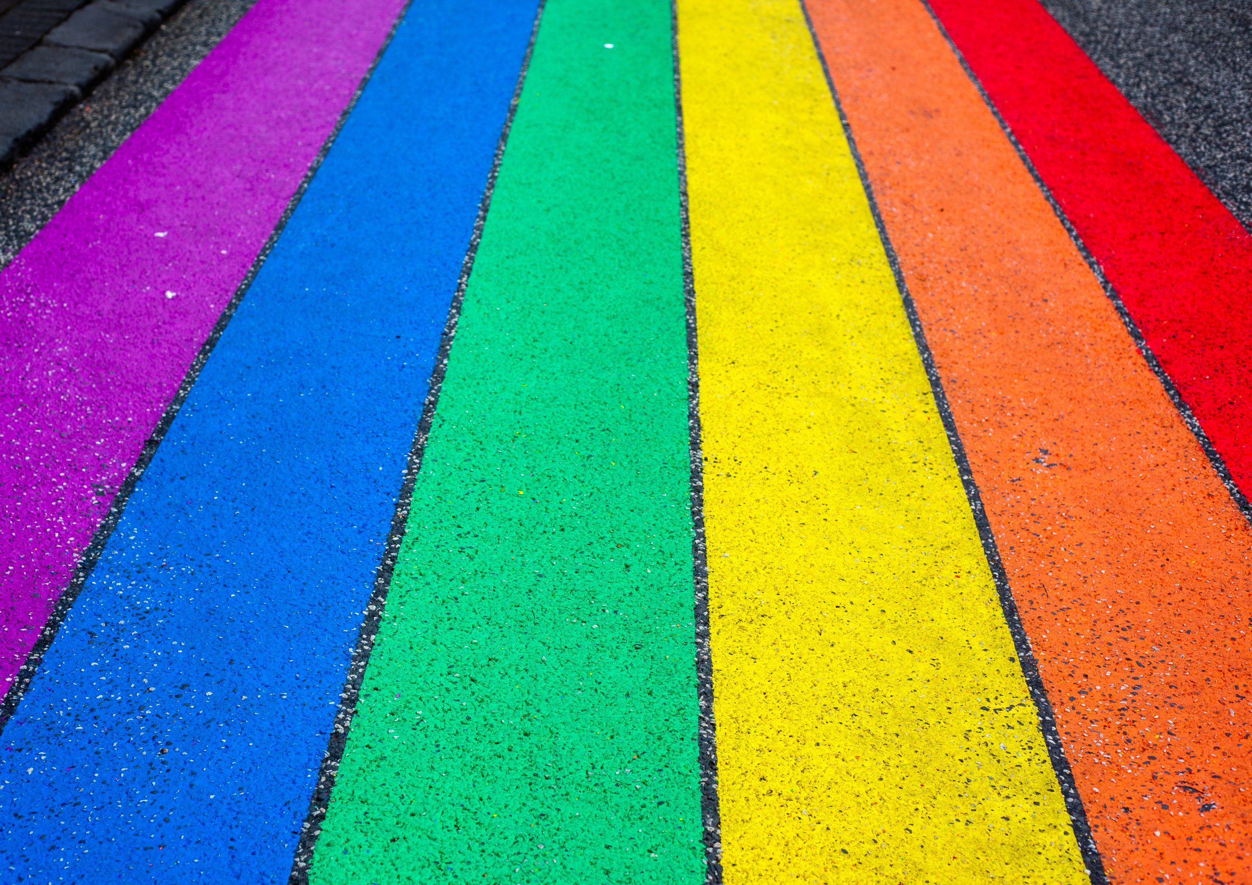 jasmin-sessler-VxKUQY3tLNs-unsplash Photograph of rainbow stripes painted on asphalt