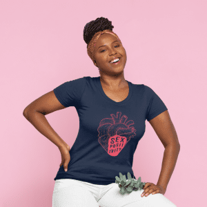 Woman with dark hair pulled into a bun with a headband and a navy blue t-shirt with a pink anatomically correct heart with the words sex positivity written in the bottom.